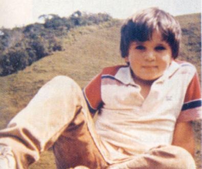 Juanes sentado en el césped de niño
