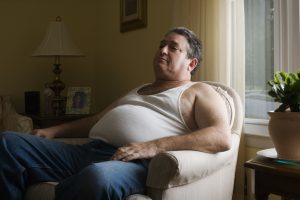 Mature overweight man sitting in armchair