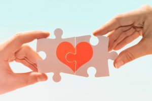 Dos personas en un puzzle dos piezas que forman un corazón.