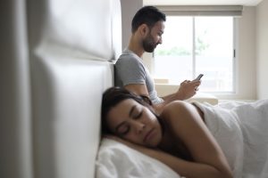 Un chico comete una infidelidad virtual mientras su pareja duerme al lado suya.
