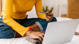 Close up woman hands using credit card to buy online on laptop
