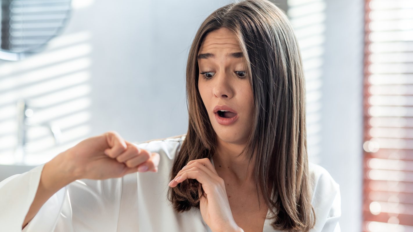 Una chica se mira con sorpresa cómo su pelo se ha debilitado.