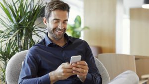 Smiling businessman using smart phone at office