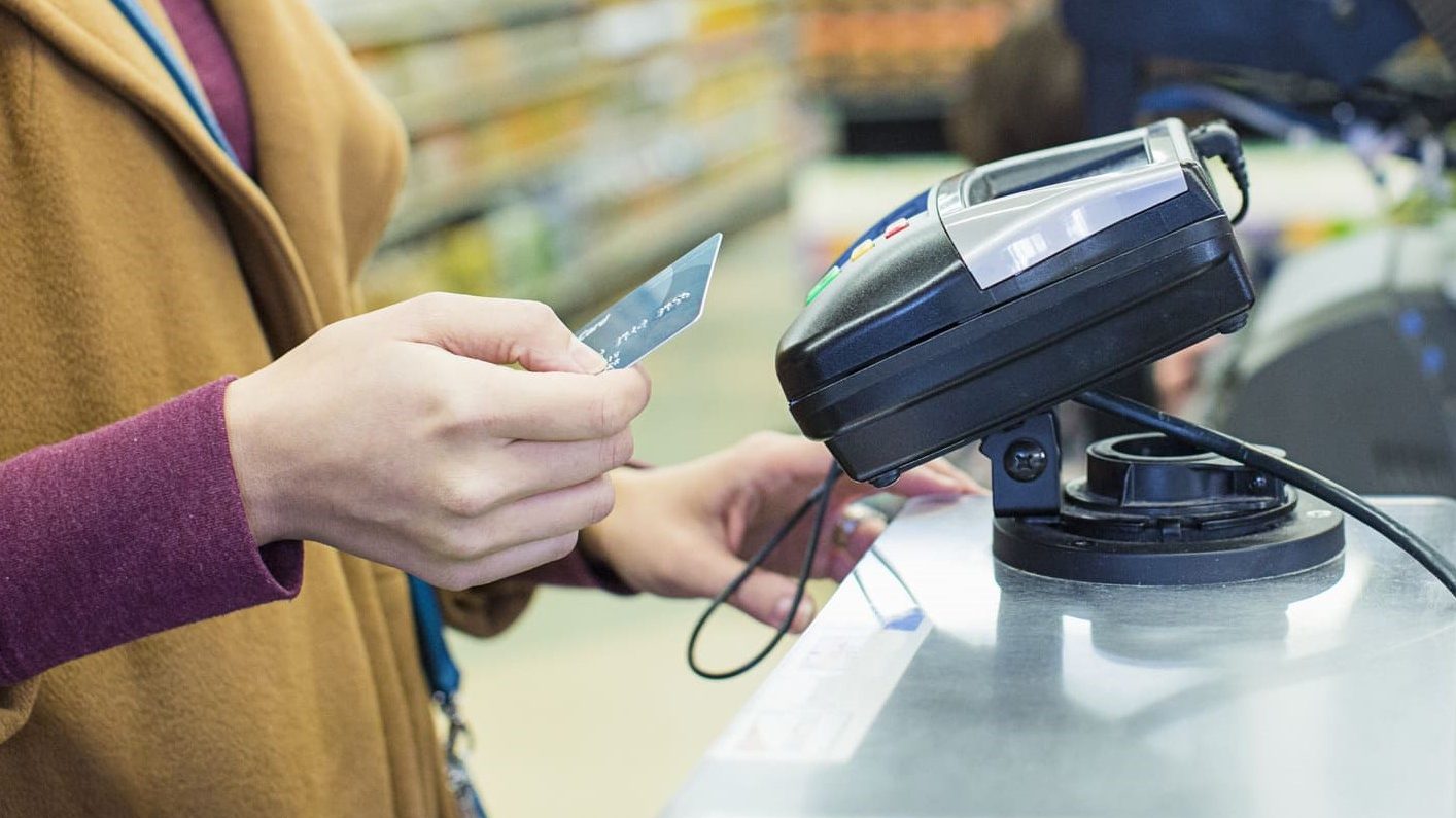 Una mujer pagando con tarjeta en el supermercado.