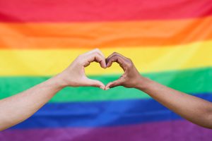 Dos personas haciendo un corazón con las manos luchando con la homofobia, la transfobia y la bifobia.