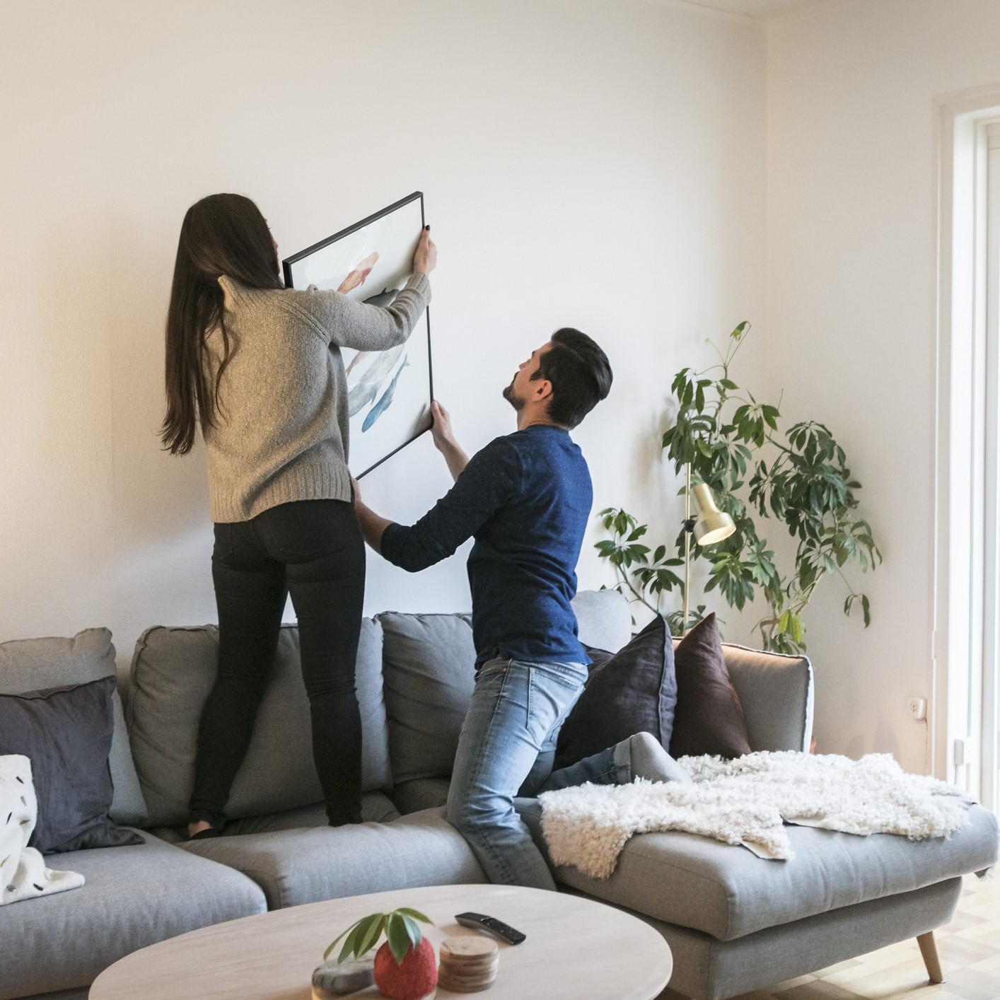 Una pareja colgando un cuadro en el salón.