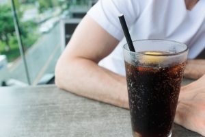 Una persona bebiéndose un vaso de Coca-Cola.