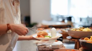 Anonymous Woman Putting Food on the Plate in the Hotel