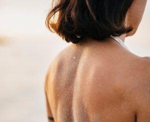 Espalda de una chica llena de arena.