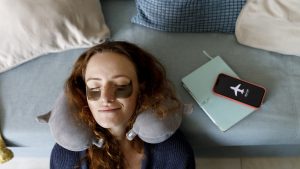 Redhead woman leaning head on sofa with smart phone on airplane mode in living room at home