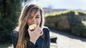 Portrait of young women eating apple outside