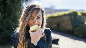 Portrait of young women eating apple outside