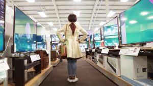 Young woman in shop looking at televisions