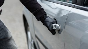 car thief hand pulling the handle of a car