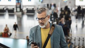 Male commuter using smart phone on escalator