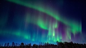 Very strong northern lights in green and purple on the nightsky.