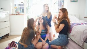 Four teenage girls getting make up ready in bedroom