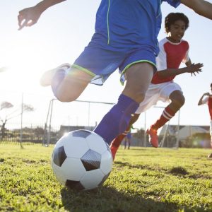 Close up of boy kicking soccer ball