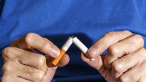 Hands breaking a cigarette on a blue background.  New Year's resolution.