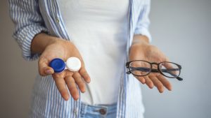 Young woman choosing between contact lenses or glasses