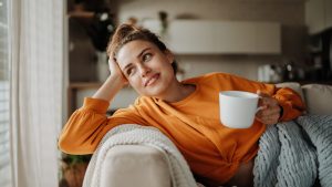 Young woman resting on sofa with cup of tea.