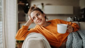 Young woman resting on sofa with cup of tea.