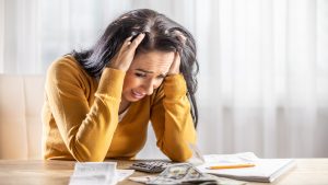 Upset young woman looking at her shopping receipt and shocked at the price.