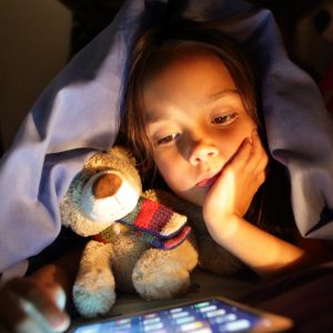 Girl in bed at night looking at tablet