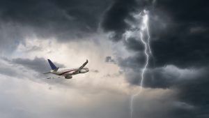 Commercial airplane flying in stormy weather with a lightning - dangerous flight and risk of aircraft accident