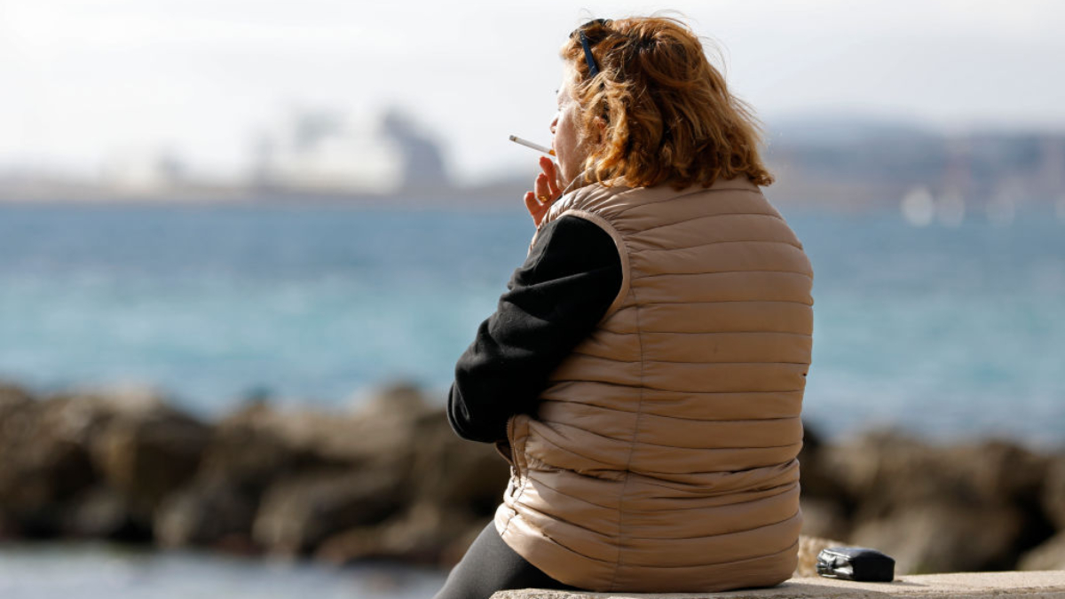 Mujer fumando en la playa