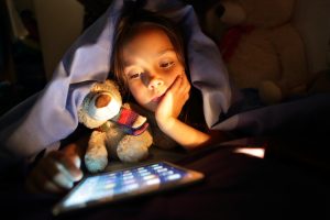 Girl in bed at night looking at tablet