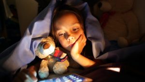 Girl in bed at night looking at tablet