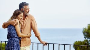 Couple embracing by railing while looking at sea
