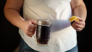 Overweight woman with mug of beer and chips