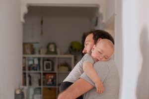 Dad putting to sleep baby boy in his arms