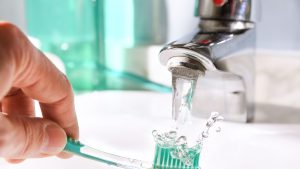 Daily Cleaning Of The Toothbrush After Use In Bathroom Sink