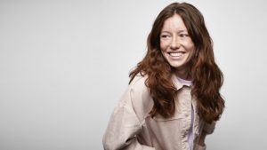 Portrait of Ginger Young Smiling Woman Looking Over her Shoulder against White Background