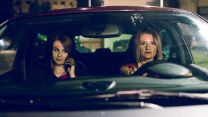 two women females in the car driving at night friends mother and daughter sisters travel journey road trip